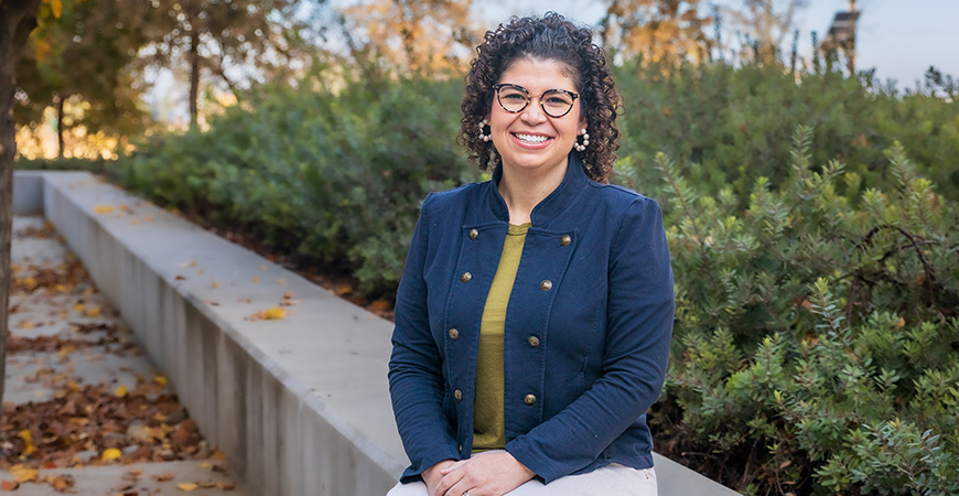 UC Merced graduate student Karla Seijas siting on concrete wall.