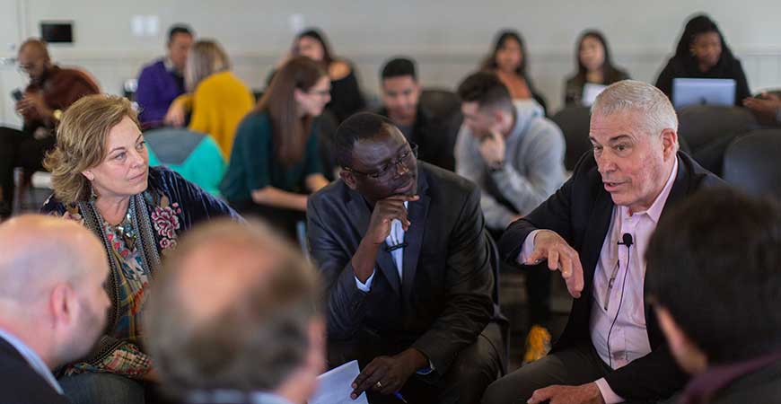 A group of people seated in a circle formation engage in discussion.