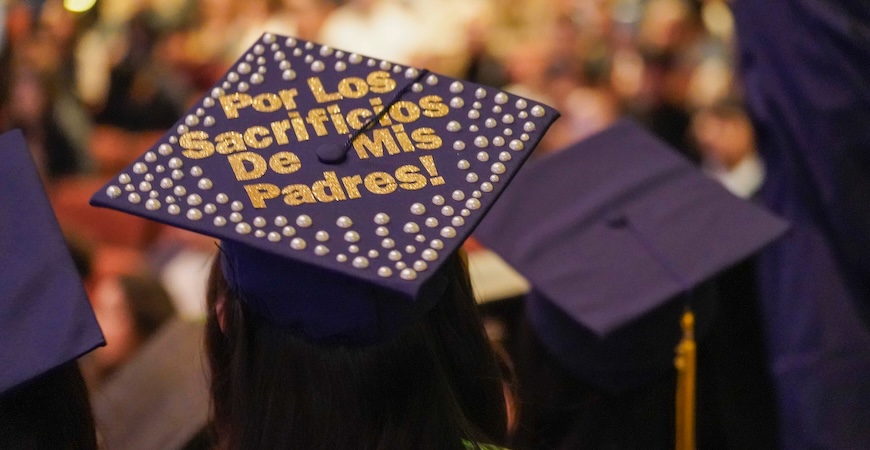 Photo depicts a graduation cap with writing on it in Spanish at UC Merced's commencement.