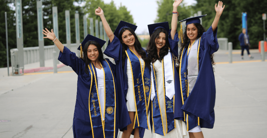 Recent female UC Merced graduates wave to the camera